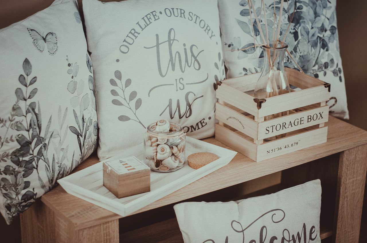Rustic home décor setup with pillows, wooden storage box, and vase on a wooden shelf, indoor cozy scene.