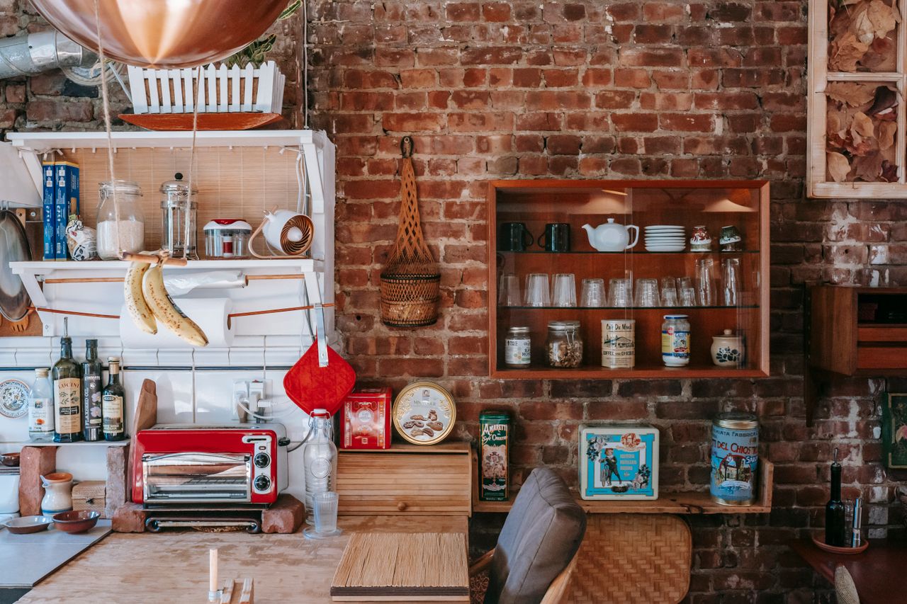 Vintage interior design with many cupboards filled with various dishware and decorations against shabby brick wall