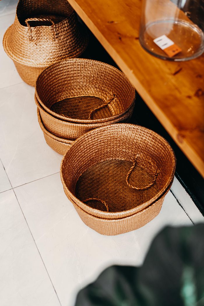 From above wicker baskets stacked together on tiled floor near shelf in workshop
